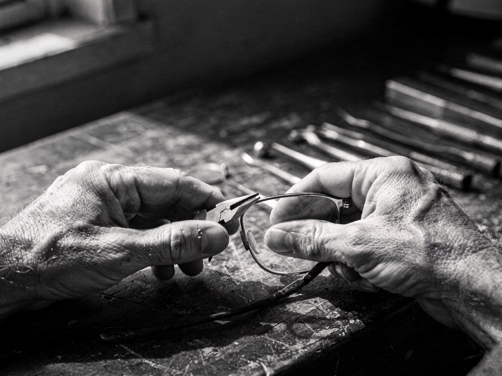An optician adjusting a spectacle frame by hand with precision pliers